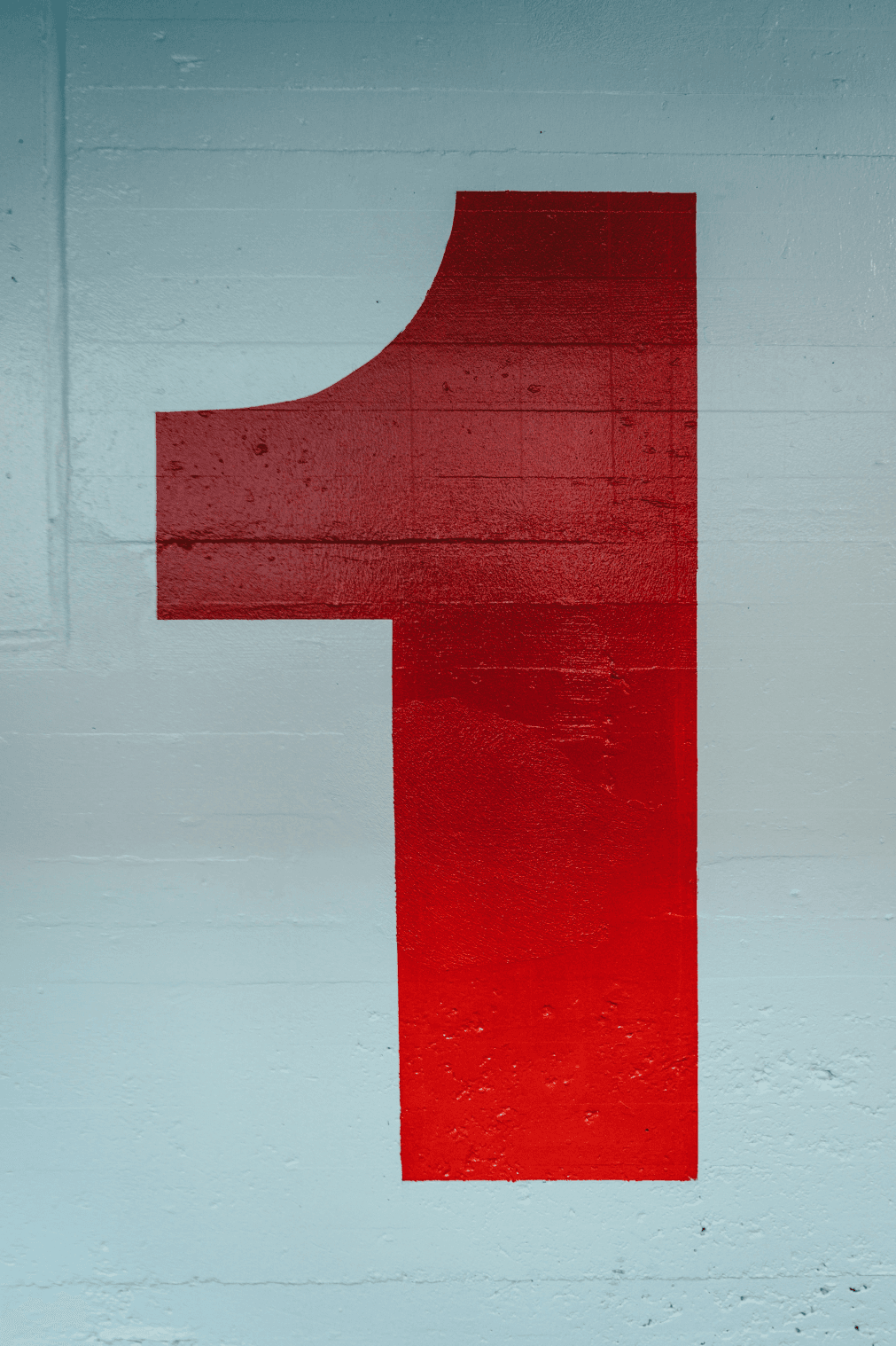 Large red number '1' painted on a light blue concrete wall, creating a bold and minimalistic design.